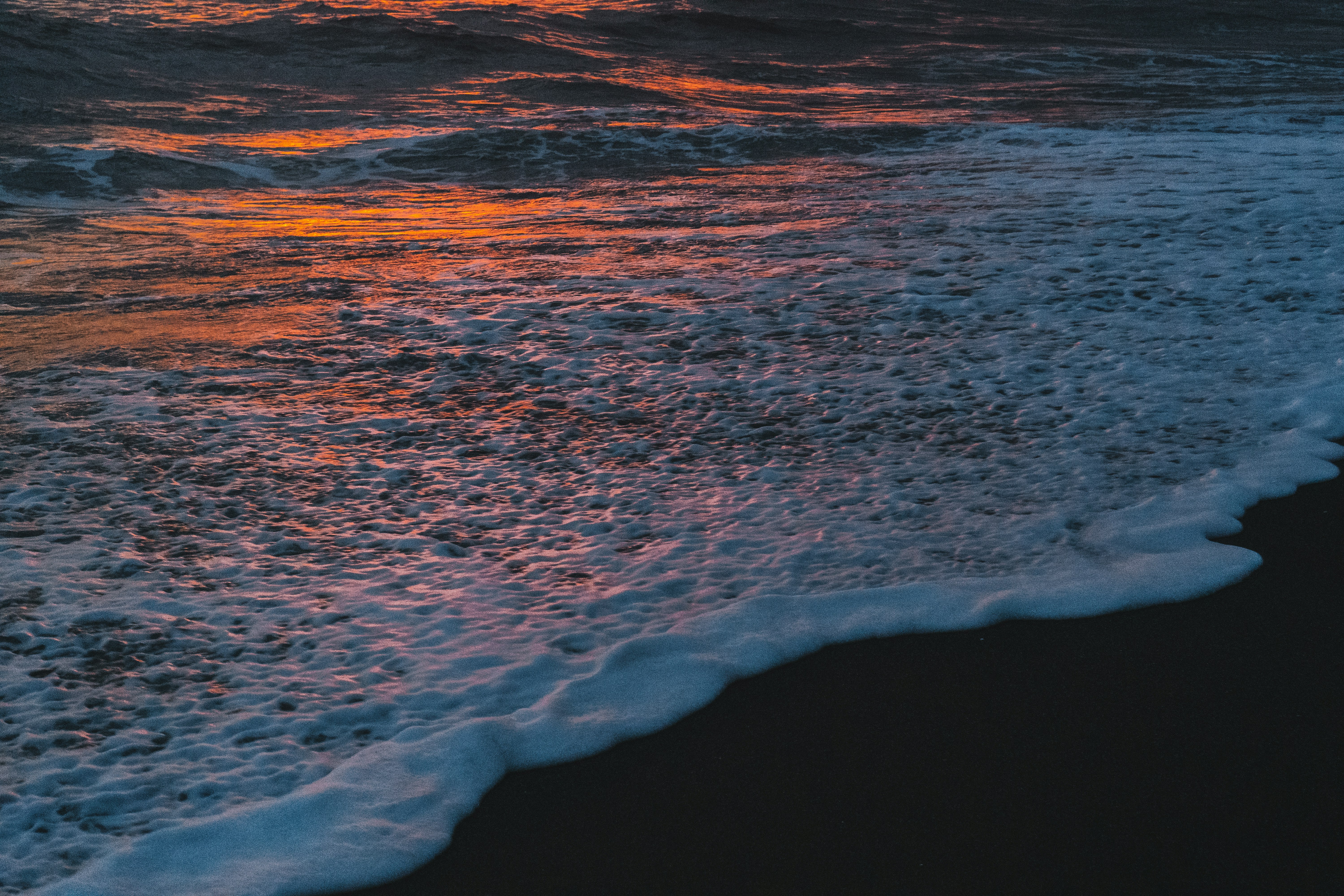 ocean waves crashing on shore during sunset